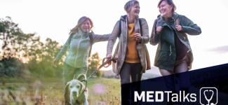 Image of three people and a dog walking on a hike