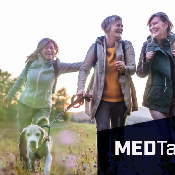 Image of three people and a dog walking on a hike